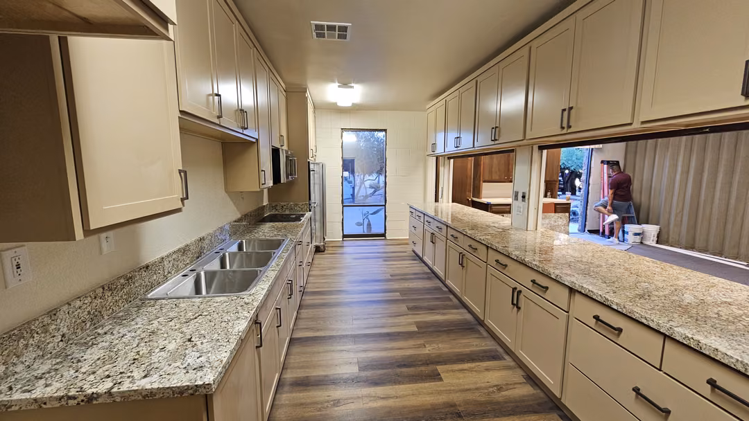 Long kitchen with cream cabinets and granite counters